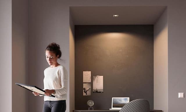Kvinne beundere et bilde i en gang som blir lyst opp av Philips spotlights