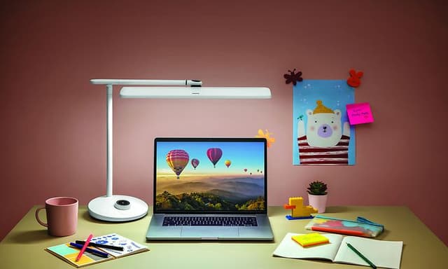 Philips skrivebordslampe som lyser over en bærbar PC på skrivebord