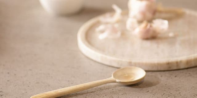 A spoon and plate with garlic on a dekton worktop