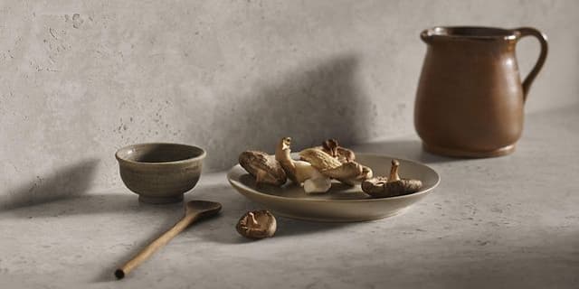 Plate with mushrooms, a spoon and a jug on a dekton worktop