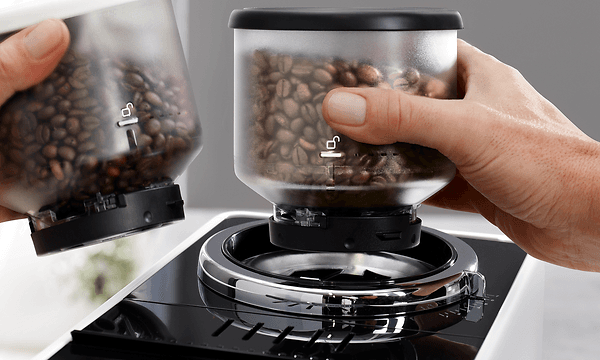 Delonghi Rivelia Bean Adapt - Nærbilde av hender som holder bønnebeholdere