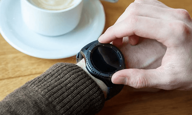 Person checking smart watch whilst drinking coffee