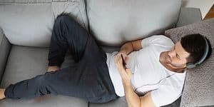 Mand på sofa med hovedtelefoner lytter til musik