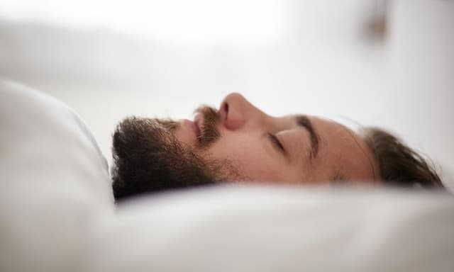 Mand med lukkede øjne på en pude