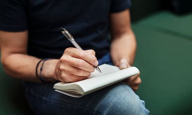 Me-time - man writing on a note block with a pen