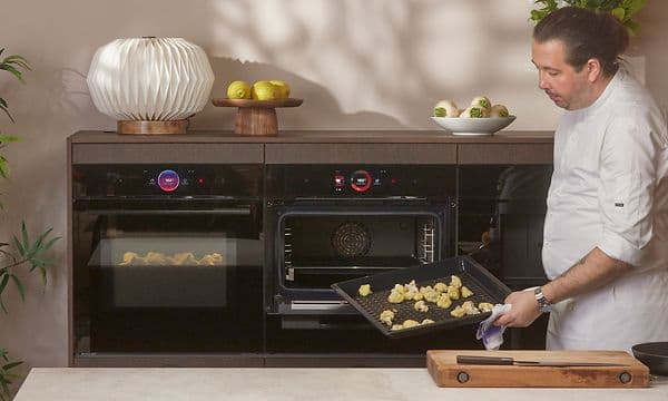 Bosch accent line in the background of chef showing fried chicken on the the Air Fry and Grill tray