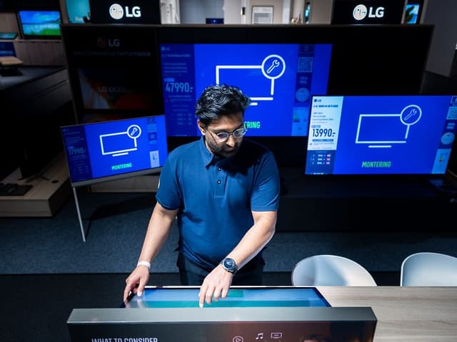 Elkjøp Bedrift Key Account Manager Waqas Ahmad står foraen tv-skjerm i ulike størrelser