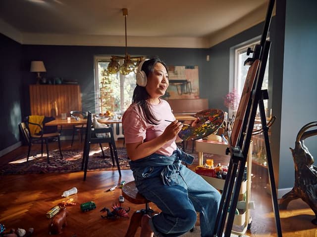 Woman with headphones painting in a living room