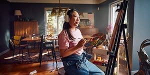 Woman with headphones painting in a living room
