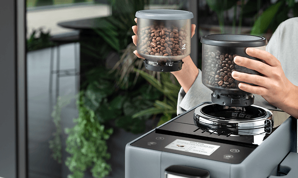 Nainen vaihtaa Delonghi Rivelia -kahvikoneen papusäiliön toiseen