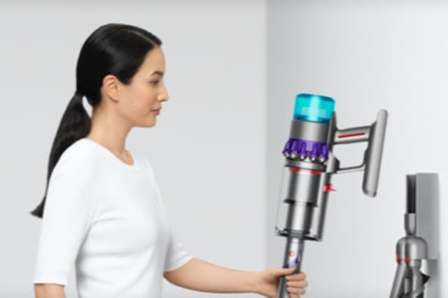 Nainen asettaa Dyson Gen5detect -imurin sen seinätelakkaan