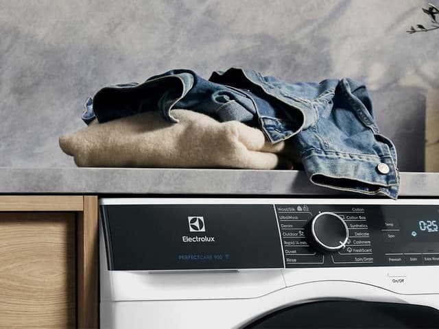 Electrolux vaskemaskin og klær liggende på toppen klare til vask