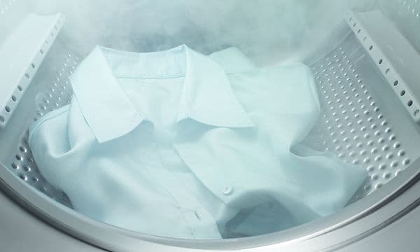 En hvit skjorte blir dampet inne i en Electrolux vaskemaskin