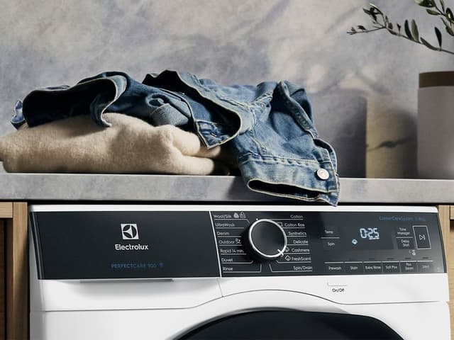 Electrolux-pyykinpesukone ja kasa vaatteita sen päällä odottamassa pesua