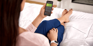 Smarttelefon som viser Garmin Connect-appen i hånden på en dame som sitter i sengen
