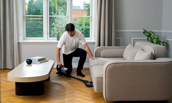 Mann støvsuger under sofaen med Nilfisk S1 Pet Care