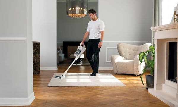 Man dammsuger vit matta med Nilfisk S1 Home plus