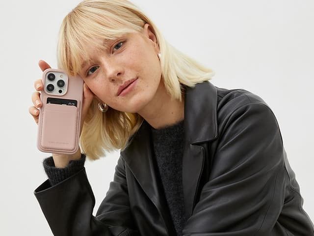 Kvinne lener seg mot telefonen som har IDEAL OF SWEDEN lommebokdeksel