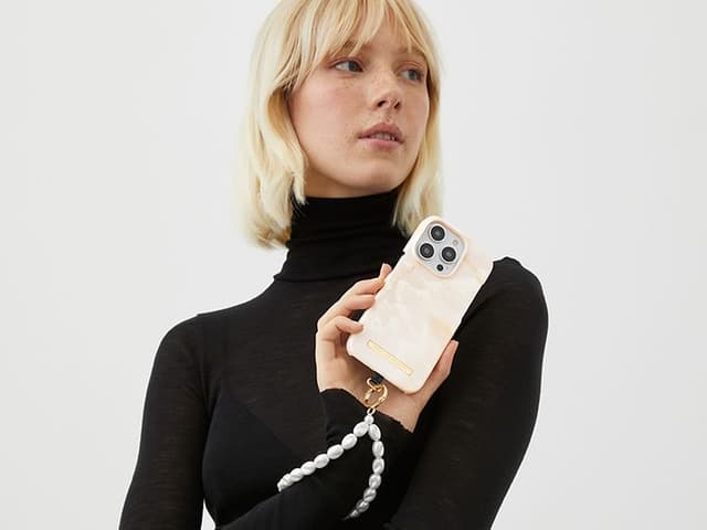 Kvinna som håller sin telefon framför sig som har IDEAL OF SWEDEN armband