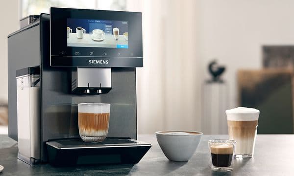Siemens EQ900 automatisk kaffemaskin på ett bord bredvid tre olika typer av kaffekoppar