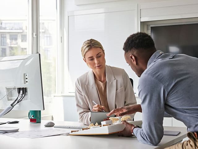 Woman working with PC using Microsoft 365 Office and discussing with a man
