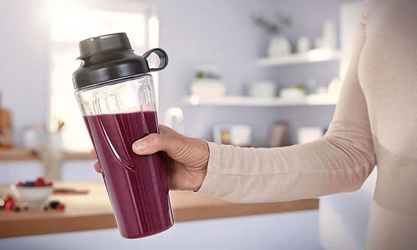 Kvinne holder Bosch-blenderens ToGo -flaske fylt med smoothie i hånden