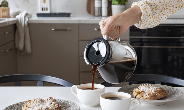 Woman pouring coffee into cups from coffee pot