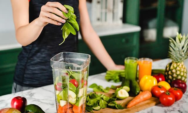 Nainen valmistaa blenderillä smoothieta vihanneksista