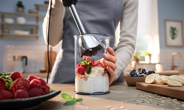 Person som använder Bosch ErgoMaster Series 6 stavmixer för att blanda yoghurt med frukt och bär