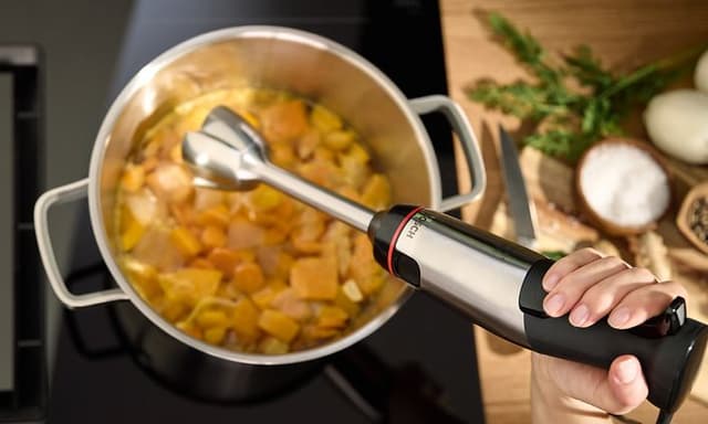 Person som använder Bosch ErgoMaster Series 6 stavmixer till ren soppa som kokar i en gryta