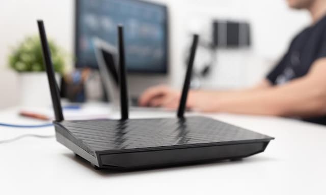 Router on a desk with a man typing on a computer in the background