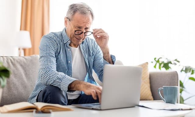 Older man squinting at laptop