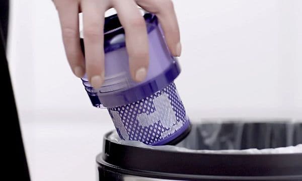 Henkilö poistaa irtopölyä Dyson-pölynimurin suodattimesta