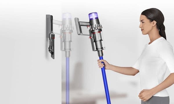 Kvinna placerar Dyson-dammsugare i väggdockan för laddning