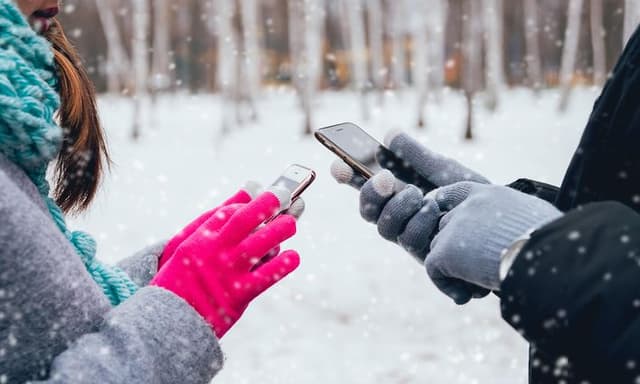 To personer med hver sin mobil ute i snøen