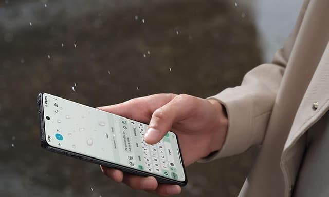 Telecom - OnePlus - OnePlus 12 - En person, der chatter på sin OnePlus 12 i regnen