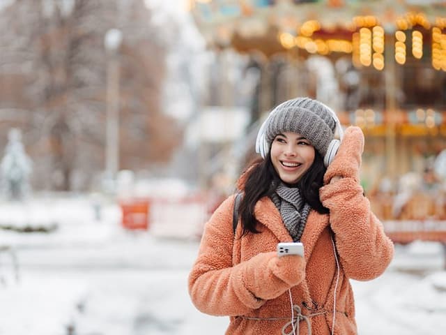 Girl with headphones and mobilephone in her hand enjoying outside on a winter day