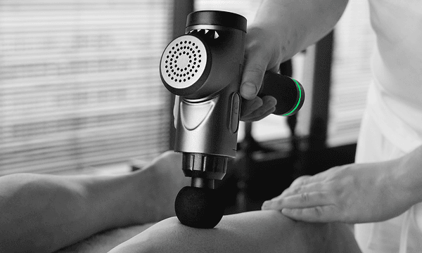 Terapeut som använder en RE-massagepistol på en patient