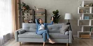 Luftkvalitet - Kvinde i en sofa med fjernbetjening til varmepumpe