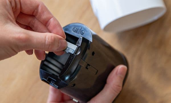 Hånd setter inn et SIM-kort i en Arlo Go V2-sikkerhetskamera