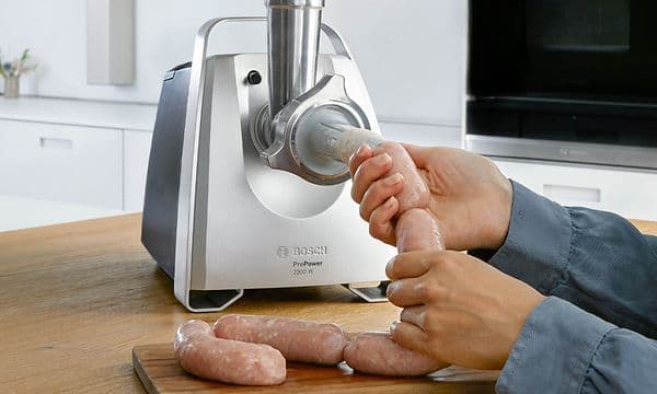 Person lager pølser med hjelp av pølsestapperen til Bosch-kjøttkverner