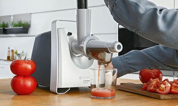 Person making fresh tomato juice with Bosch meat grinders fruit press attachment