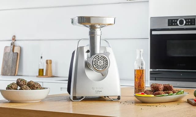 Bosch meat grinder on the kitchen worktop next to meat balls and vegetables