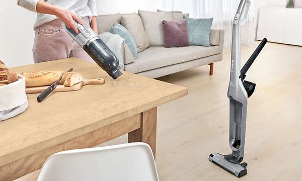 Woman using Bosch Serie 4 Flexxo's handheld vacuum to clean crumbs of the dining table