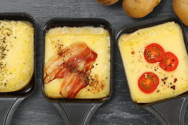 Tre raclette-jern med ost og topping