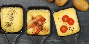 Tre raclette-jern med ost og topping
