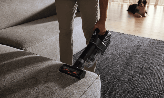 Person vacuuming a a sofa with compact electrobrush 