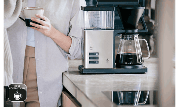 Melitta One kaffemaskine på et køkkenbord og en person der drikker kaffe