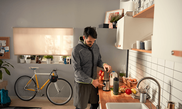 Treenivaatteisiin pukeutunut mies valmistaa smoothieta tehosekoittimella