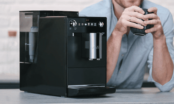 Melitta Latticia OT kaffemaskin ved siden av en mann som drikker en kopp kaffe